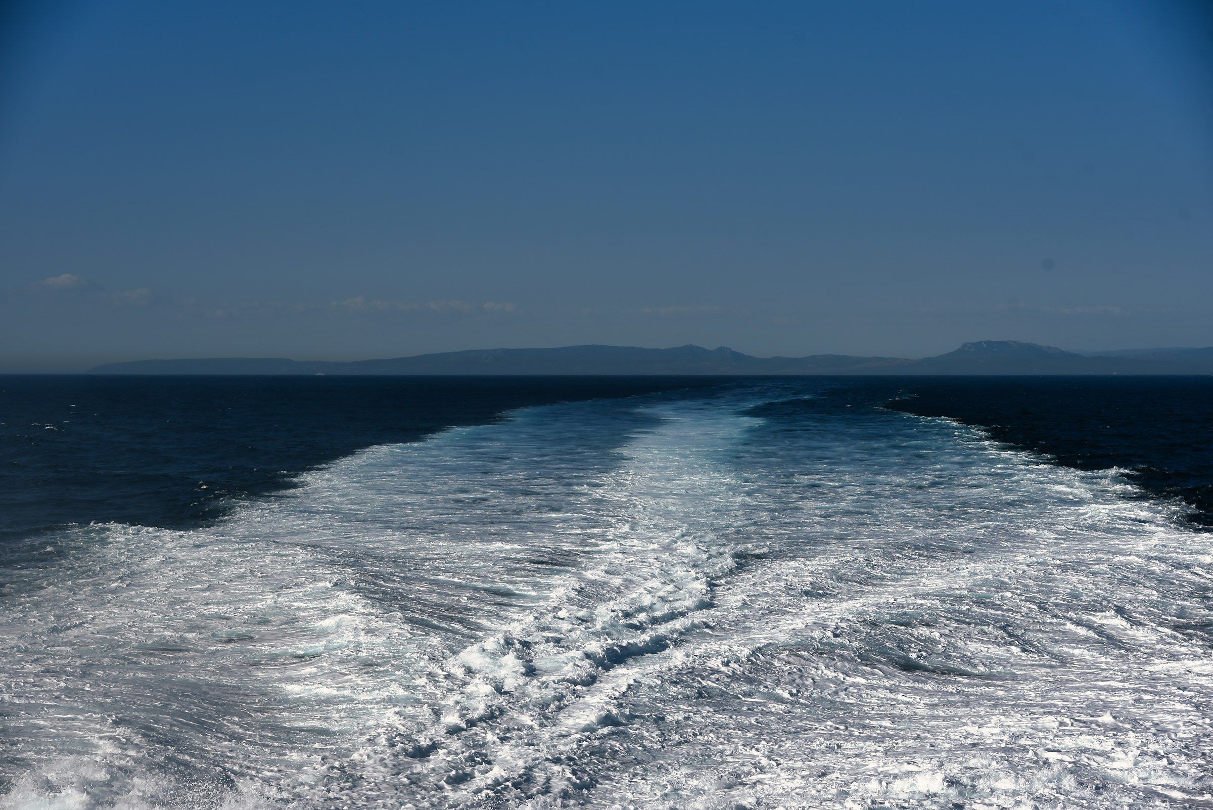 White wake trailing behind a ship on deep blue sea